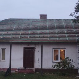 J.W.bud - Dom jednorodzinny z widoczną konstrukcją drewnianą dachu przed położeniem pokrycia, drabina oparta o ścianę, ceglany komin.