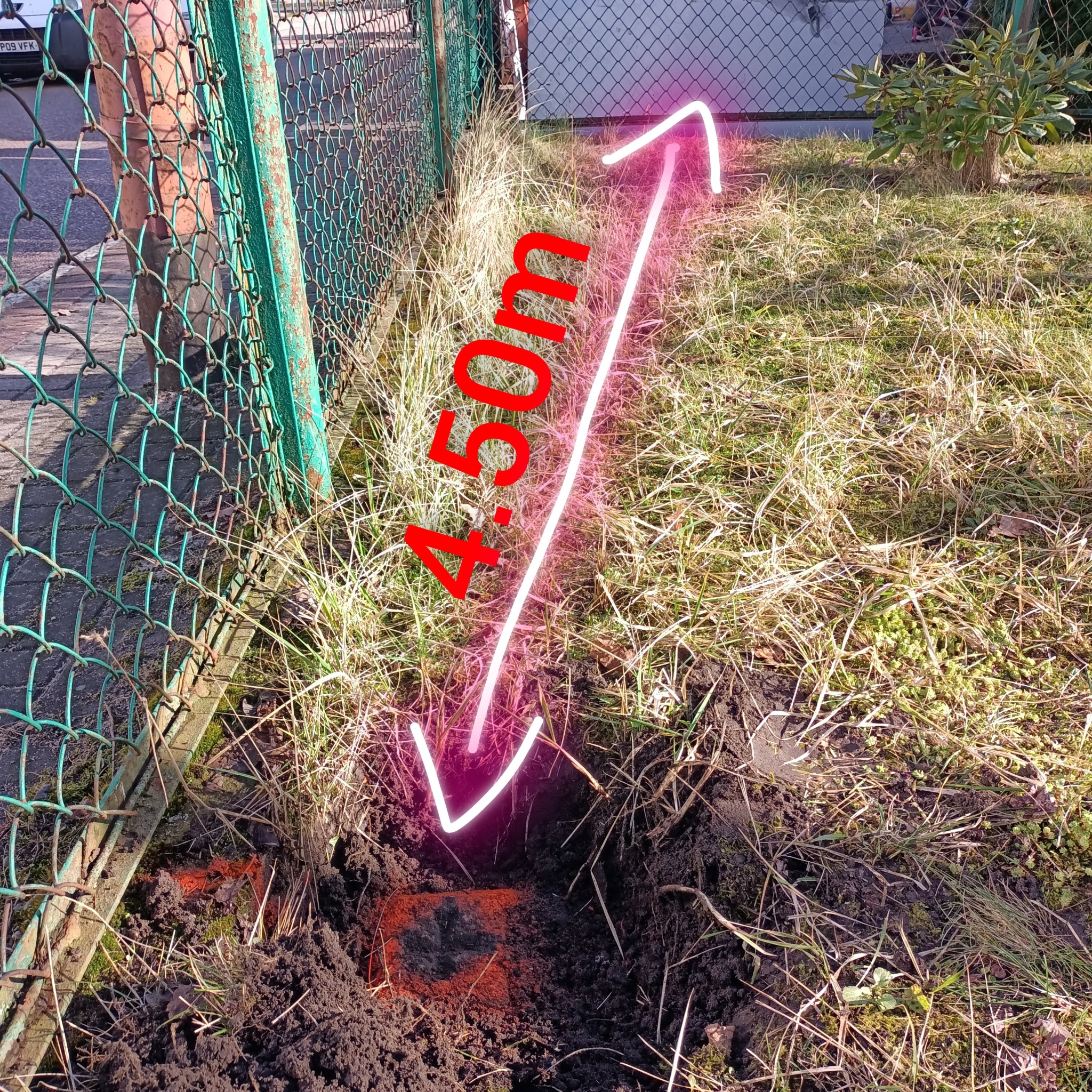 Pomiar odległości 4.50m od ogrodzenia z siatki do punktu w ziemi, zaznaczonego czerwoną farbą.