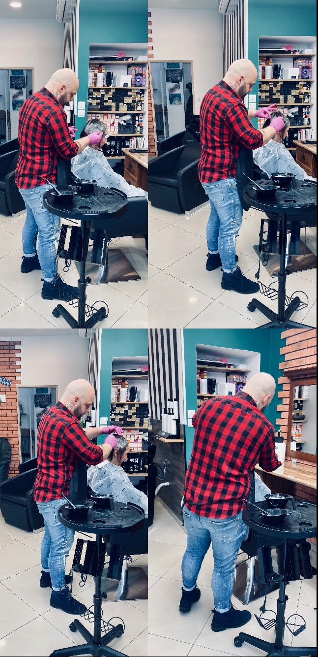 Kolorysta w czerwonej koszuli w kratę nakłada farbę na włosy klientki w salonie, widoczny stolik z miseczkami i pędzelkami.