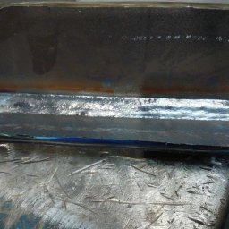 SPAWAMY NA JAKOŚĆ Marcin Dębiński - Spoina łącząca dwa elementy stalowe, wykonana w Zielonej Górze, widoczna na tle metalowego stołu warsztatowego z licznymi śladami użytkowania.