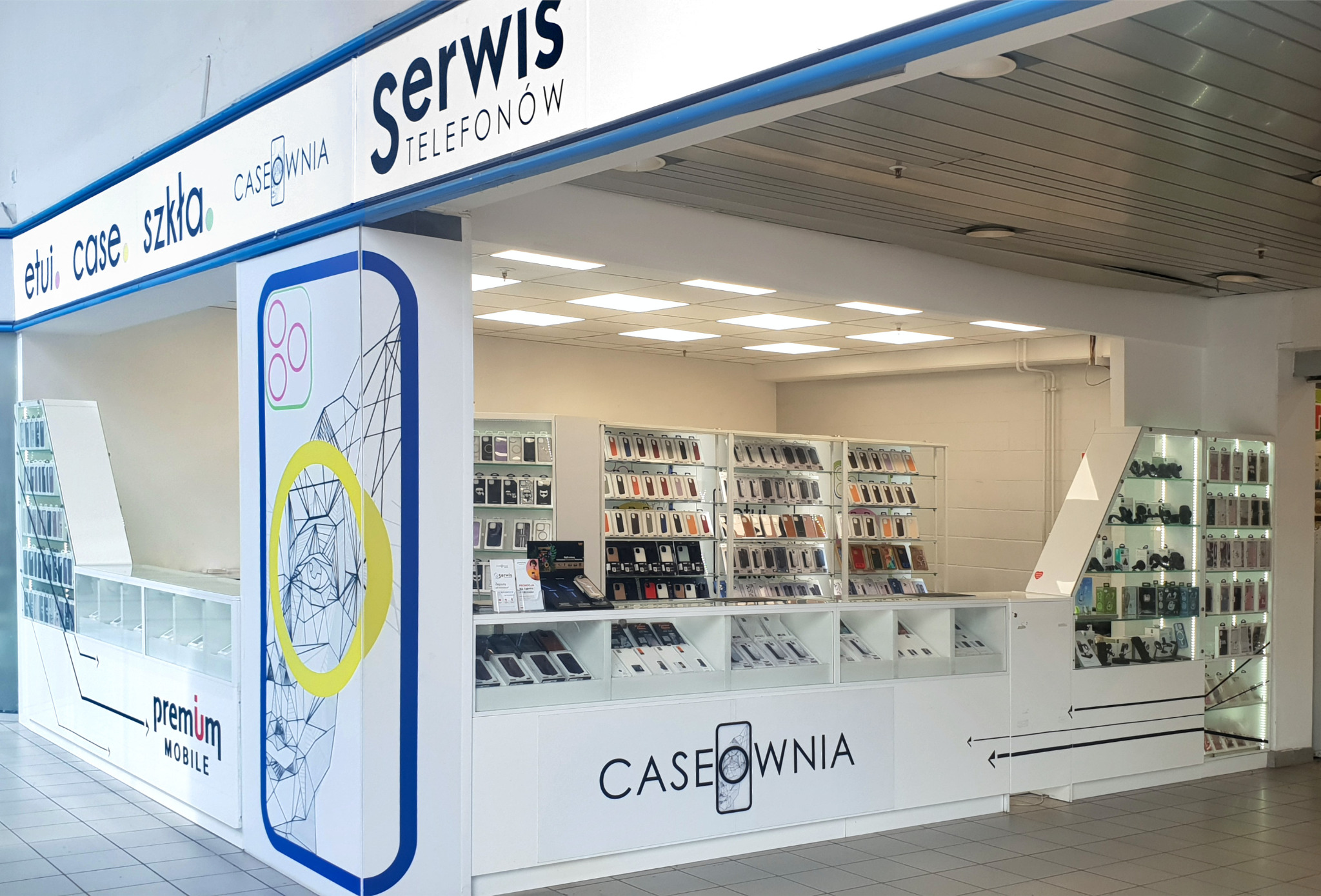 Stoisko Caseownia z akcesoriami do telefonów i usługami serwisowymi, prezentujące szeroki wybór etui i szkieł ochronnych w białych gablotach.