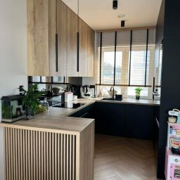 Studio dekoracji okien - Nowoczesna kuchnia w odcieniach drewna i granatu z drewnianymi żaluzjami poziomymi z czarnymi taśmami, akwarium na blacie i podłogą w jodełkę.