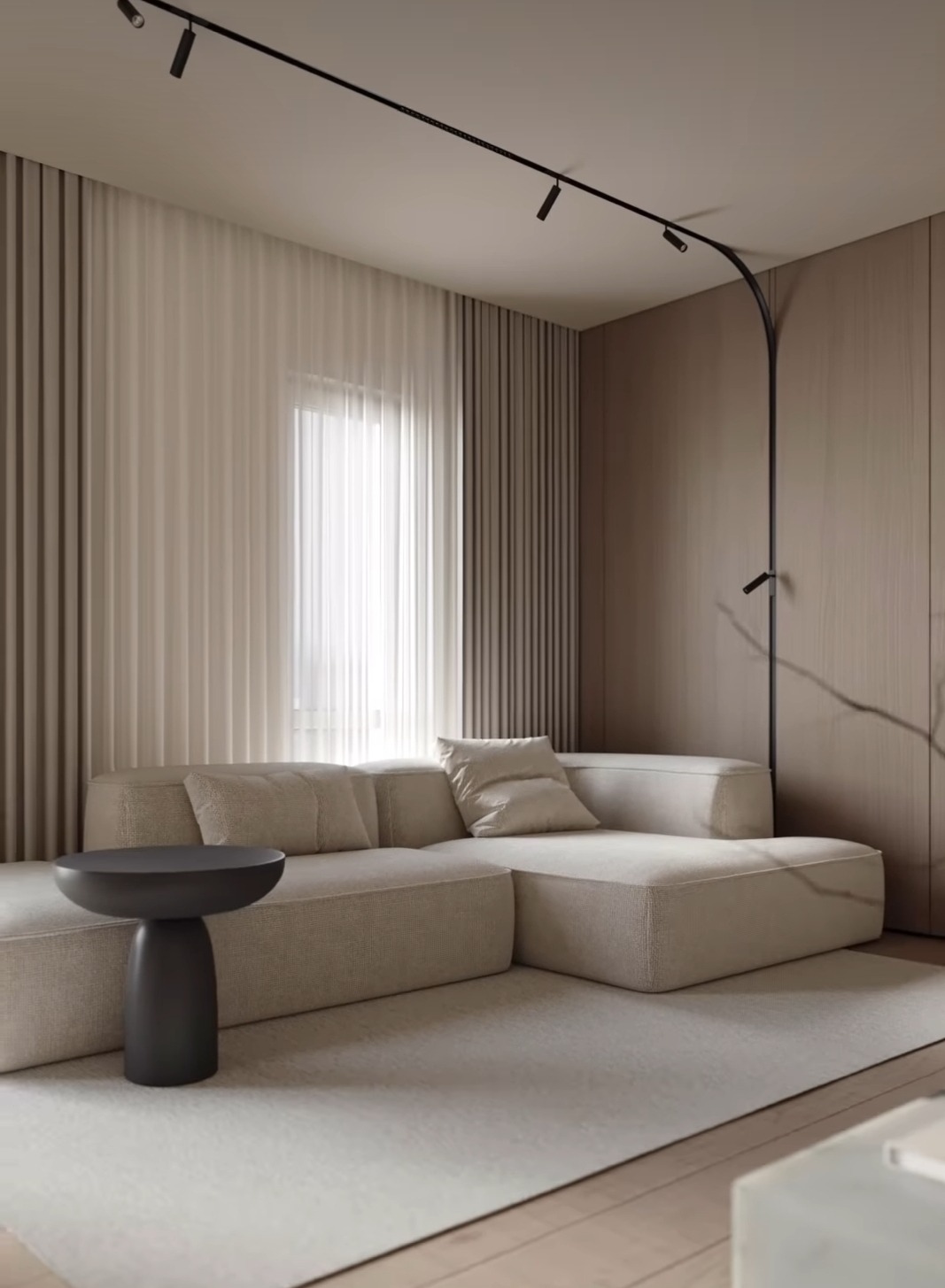 Neutralne, beżowe zasłony panelowe wiszące w salonie z narożną sofą, oświetleniem szynowym i stolikiem pomocniczym