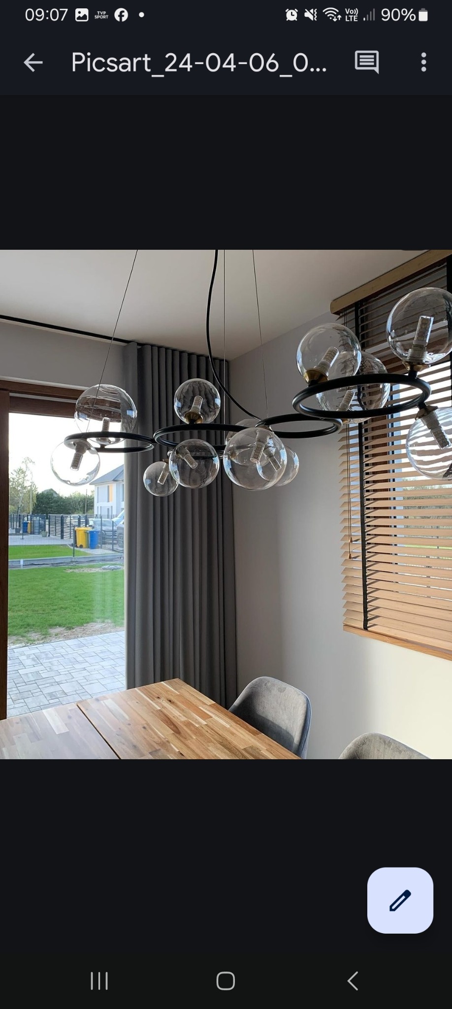 Jadalnia z drewnianym stołem, szarymi krzesłami i nowoczesną lampą wiszącą z przezroczystymi kloszami, w tle zasłony i żaluzje drewniane.