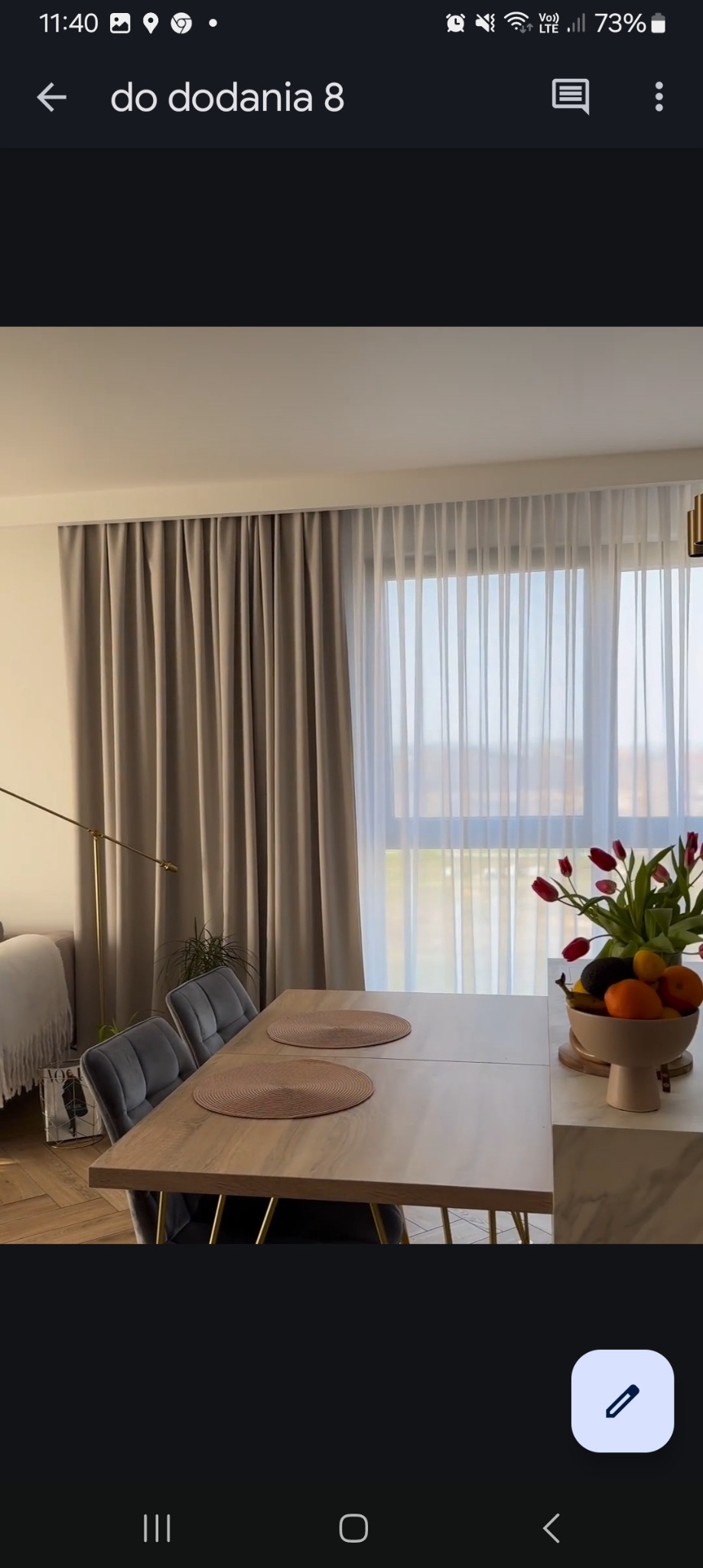 Beżowe zasłony i firanka w nowoczesnym salonie z drewnianym stołem, szarymi krzesłami i bukietem tulipanów.