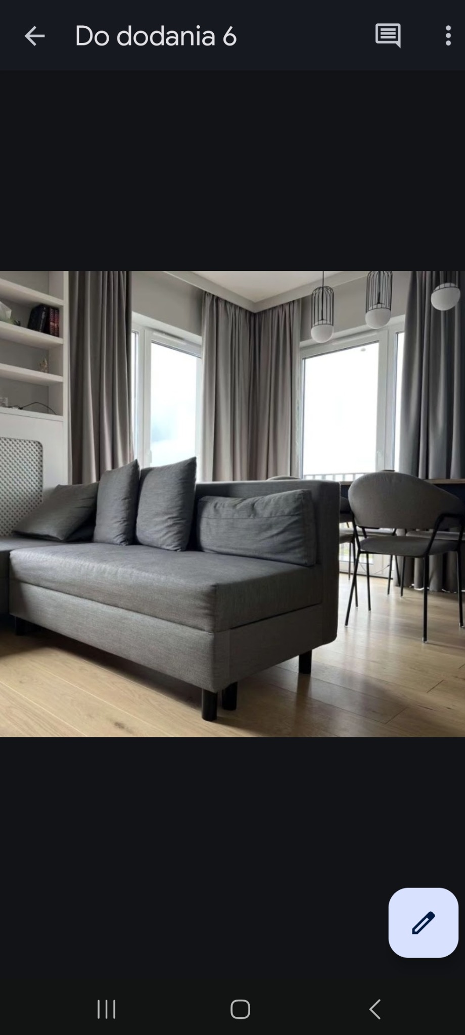 Szare zasłony w salonie z szarą sofą narożną i drewnianą podłogą, widoczne przez okno wiszące lampy.