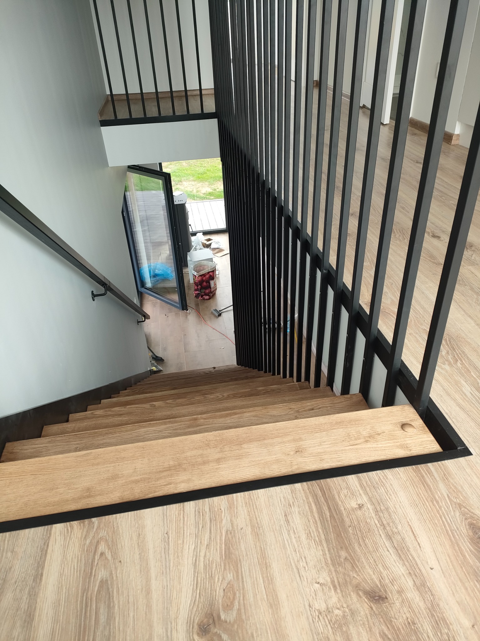 Nowoczesne schody drewniane z czarną balustradą w Bystrzycy Kłodzkiej. Widok z góry, ukazujący jasne stopnie i minimalistyczny design.