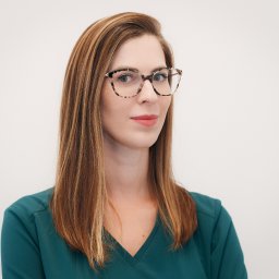 NATURAL SKIN CLINIC - salon kosmetyczny Kraków - Portret kobiety w okularach o wzorzystych oprawkach, ubrana w zielony uniform, z delikatnym makijażem i brązowymi włosami na jasnym tle.