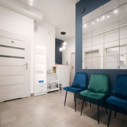 NATURAL SKIN CLINIC - salon kosmetyczny Kraków - Jasne wnętrze salonu z trzema welurowymi krzesłami w odcieniach niebieskiego i zielonego, lustrzana ściana z certyfikatami i dyplomami, oraz recepcja w tle.