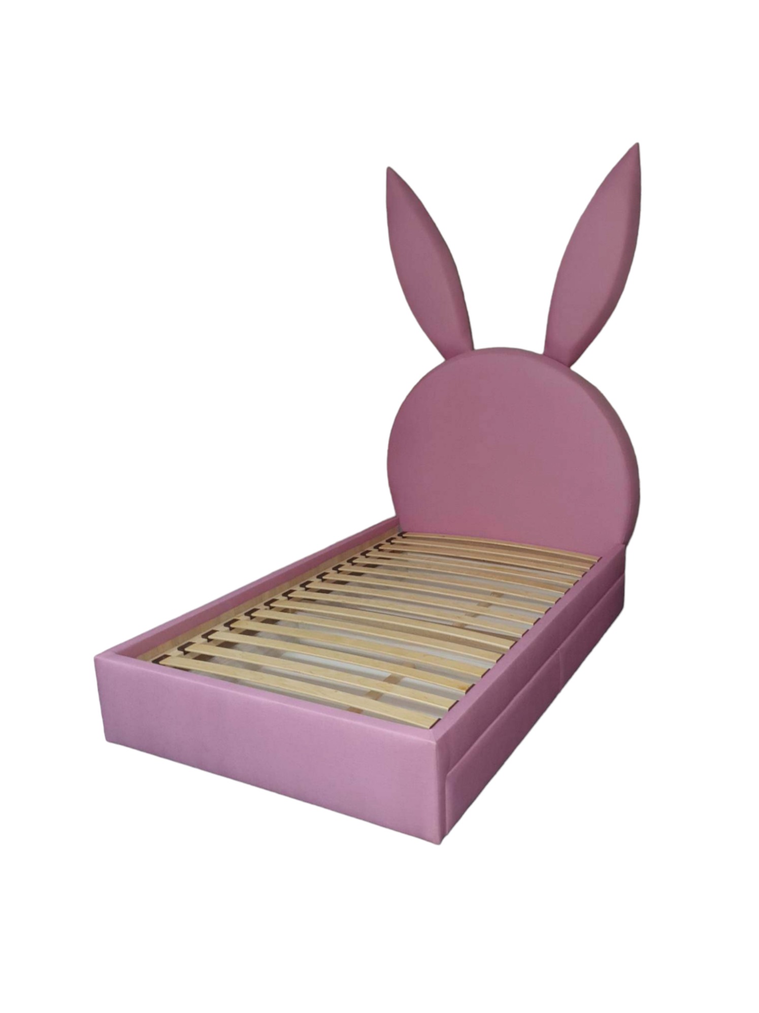 Różowe łóżko dziecięce z tapicerowanym wezgłowiem w kształcie króliczych uszu i drewnianym stelażem, sfotografowane na białym tle.