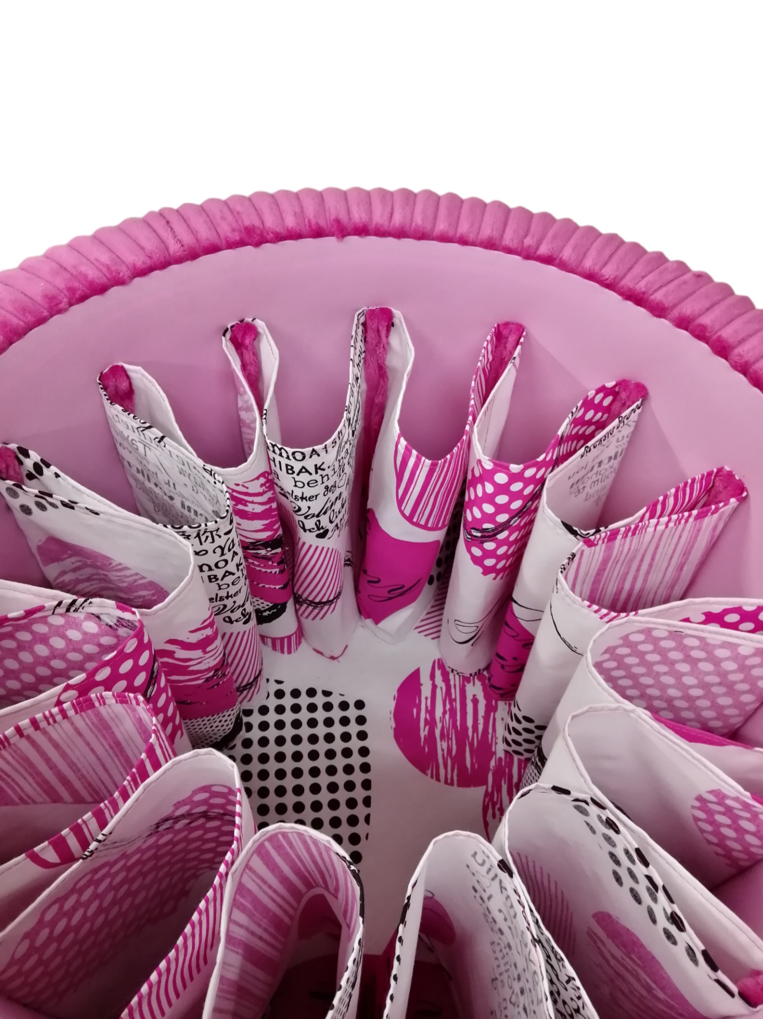 Wnętrze okrągłego, różowego pufy z tapicerowanymi przegródkami w biało-różowe wzory, widok z góry.