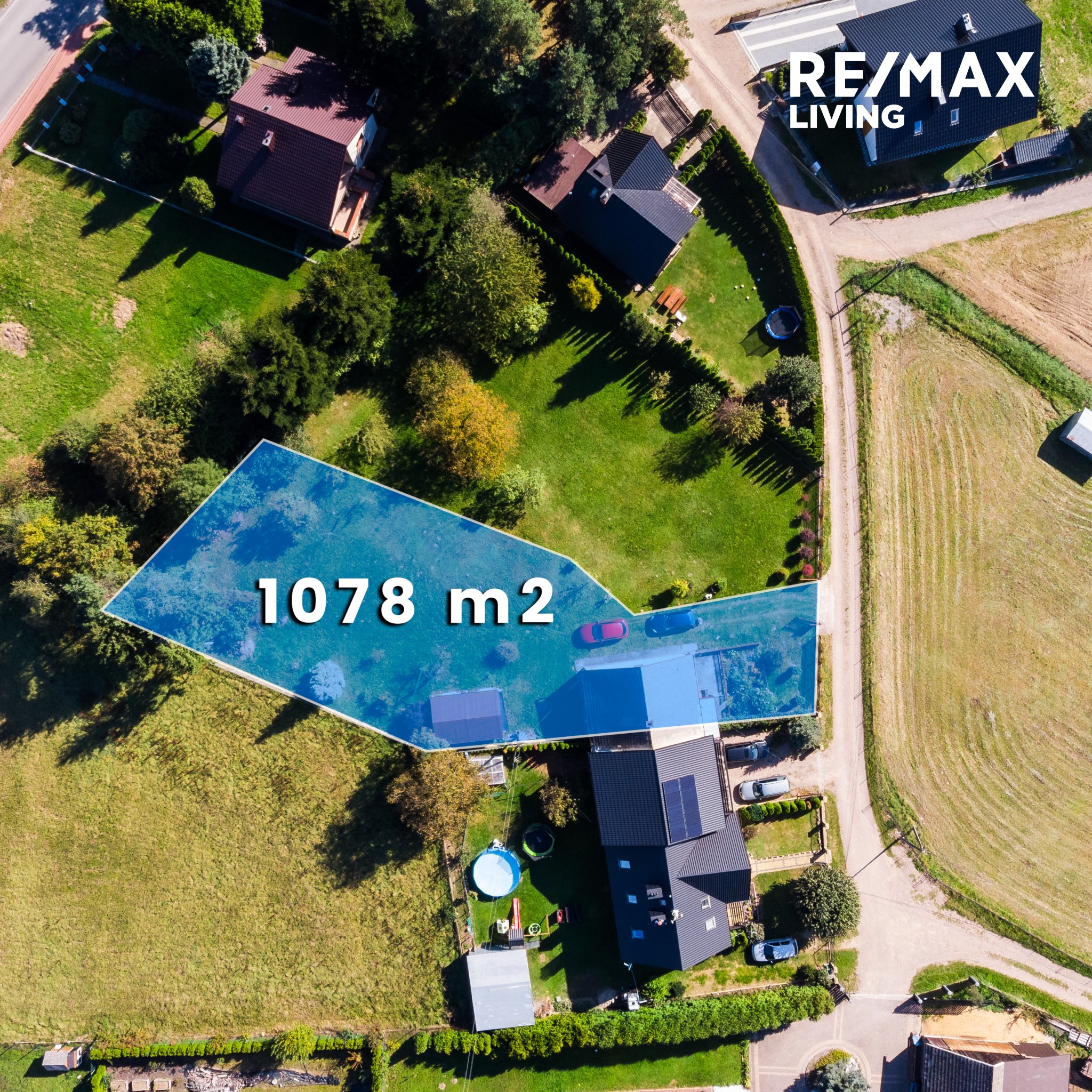 Zdjęcie z lotu ptaka przedstawia działkę o powierzchni 1078 m2 z zaznaczonym obrysem, na której znajduje się dom z ogrodem, basenem i trampoliną, a w rogu widoczne logo agencji nieruchomości RE/MAX...
