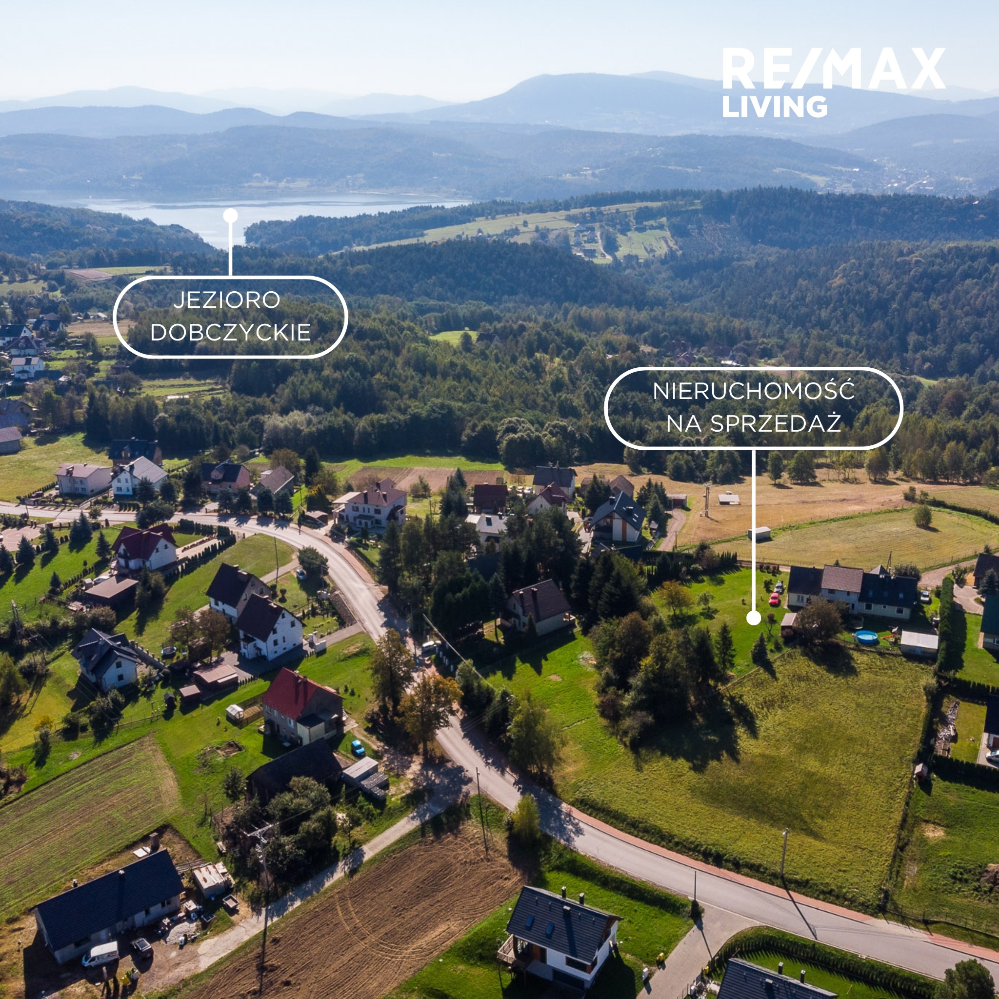Panoramiczny widok z lotu ptaka na jezioro Dobczyckie i okoliczne domy, oznaczona nieruchomość z czerwonym samochodem na sprzedaż, logo RE/MAX Living w prawym górnym rogu.