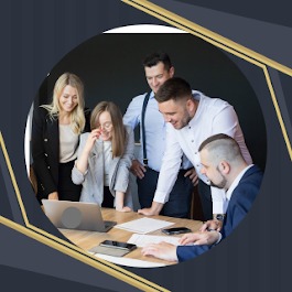 Grupa pięciu osób w biurze, pochylona nad laptopem na drewnianym stole, analizująca dokumenty. Kobieta w okularach śmieje się, a pozostali z zainteresowaniem obserwują ekran. Tło stanowi ciemna...