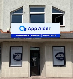 Fasada budynku z szyldem 'App Alder' oferującym usługi deweloperskie, kredyty i inwestycje, z widocznymi oknami i plakatami informacyjnymi w witrynach.