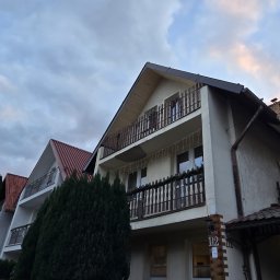 Rafał Biegacz - Widok na trzy budynki z balkonami, z których jeden ma drewniane balustrady i świąteczne lampki, a elewacja wymaga odświeżenia.