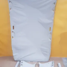 Wnętrze samochodu zdemontowane do tapicerowania: podsufitka i elementy słupków w jasnym odcieniu szarości, widoczne otwory montażowe i detale wykończeniowe.