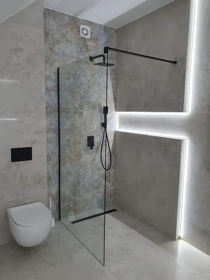 Nowoczesna łazienka z kabiną prysznicową typu walk-in, czarną armaturą, podświetleniem LED i wiszącą toaletą.