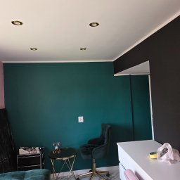 Kornobud - Pokój po malowaniu ścian na butelkową zieleń i czarno. Widoczne meble i marmurowa podłoga. Sufit biały z okrągłymi lampami.