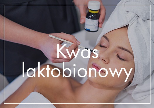 Aplikacja kwasu laktobionowego pędzlem na twarz kobiety z ręcznikiem na głowie, butelka z preparatem w tle.