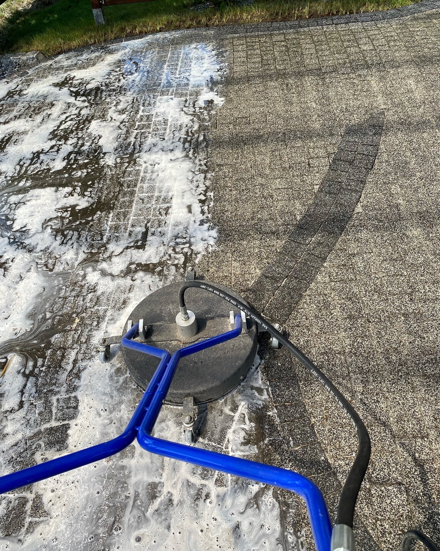 Czyszczenie kostki brukowej za pomocą myjki ciśnieniowej z okrągłą dyszą, widoczny efekt czyszczenia i brudna piana.
