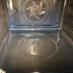 Wnętrze czystego piekarnika z widoczną grzałką i prowadnicami na blachy, po profesjonalnym czyszczeniu.