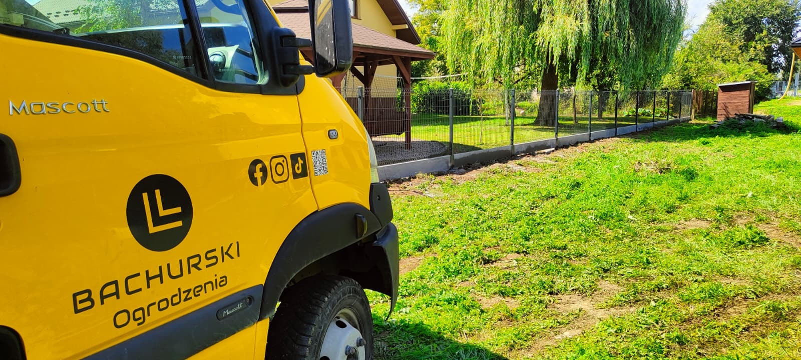 Żółty samochód firmy Bachurski Ogrodzenia na tle świeżo postawionego ogrodzenia panelowego z podmurówką. Widoczne logo firmy i ikony social media na pojeździe.