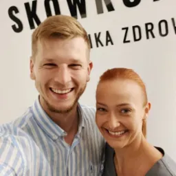 Uśmiechnięci pracownicy kliniki zdrowia 'Skowronek' pozują do zdjęcia na tle logo firmy.