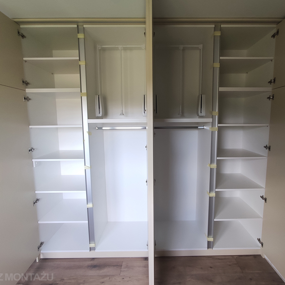 Wnętrze szafy wnękowej z otwartymi drzwiami, widoczne półki, drążki na ubrania i mechanizmy podnośnikowe, jasne wykończenie, drewnopodobna podłoga.