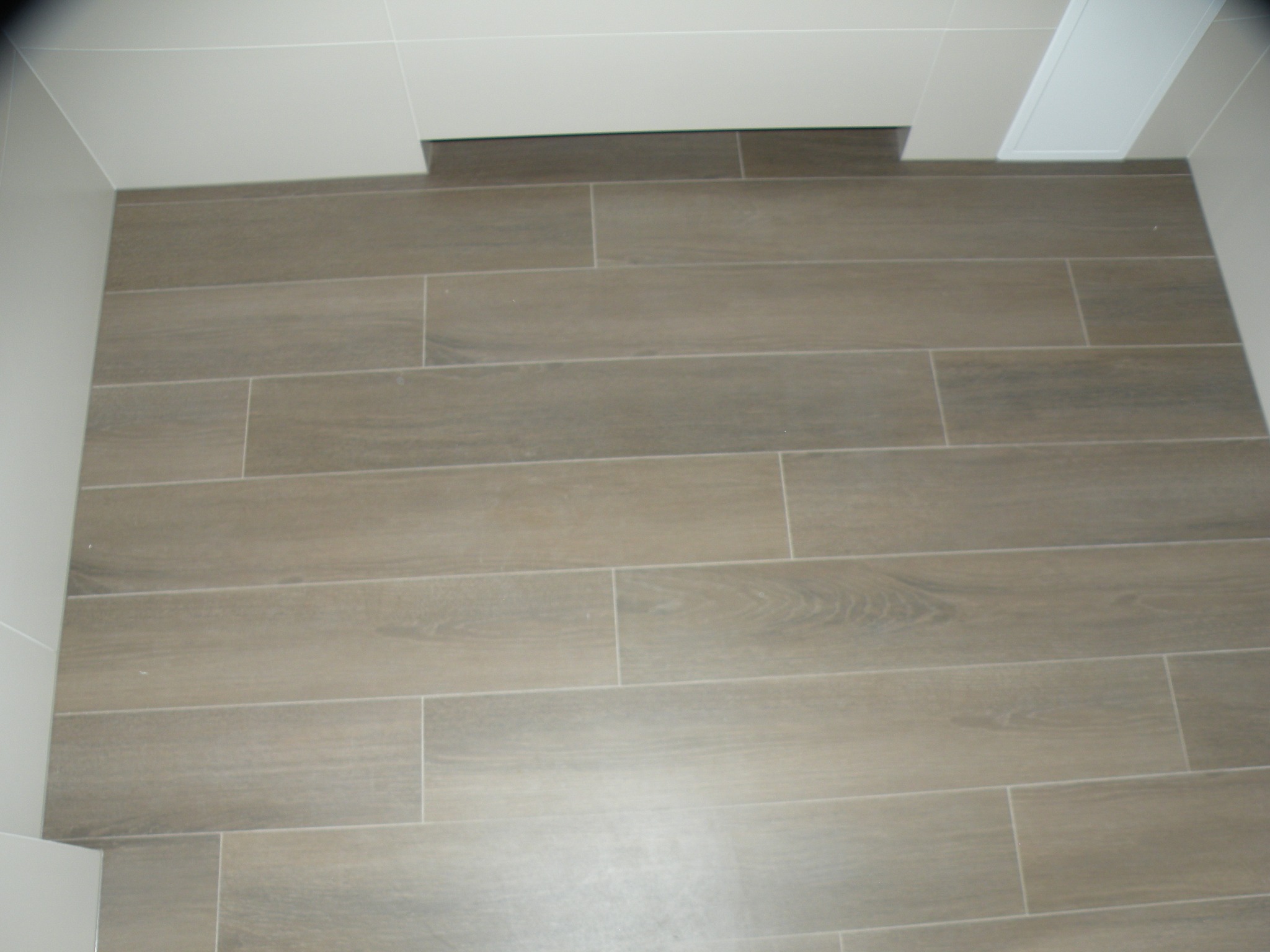 Ułożona podłoga z płytek imitujących drewno w łazience, widok z góry, neutralna kolorystyka.