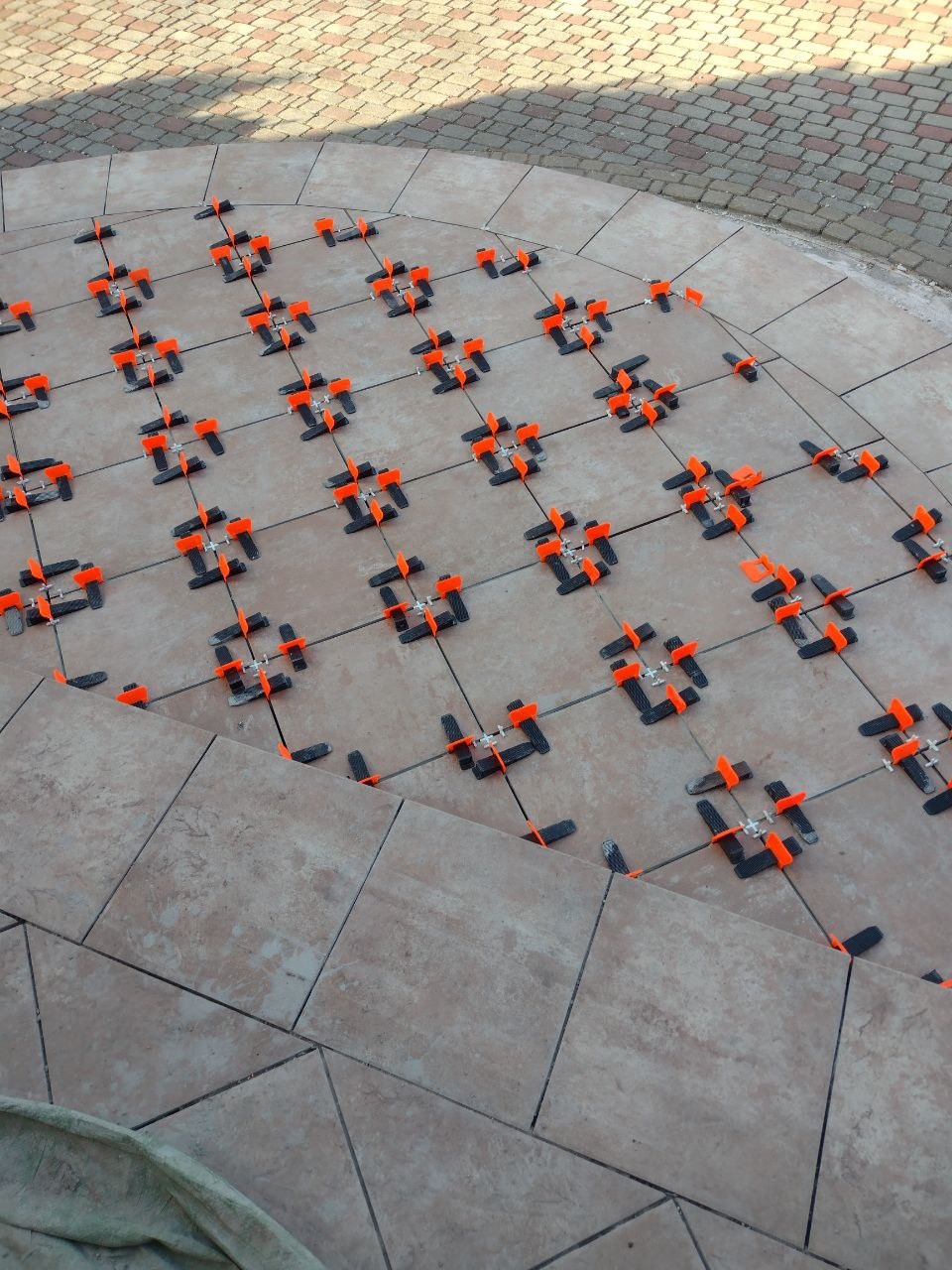 Układanie płytek na schodach zewnętrznych z użyciem systemu poziomowania płytek (klipsy i kliny).