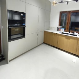 SN COMPANY SERHII NOVOMODNYI - Nowoczesna kuchnia z zabudową w odcieniach szarości i drewna, z wbudowanym piekarnikiem i mikrofalówką, oświetlona lampą sufitową z kulistymi kloszami.