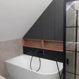 MajsterJan - Nowoczesna łazienka na poddaszu z białą wanną, czarną armaturą i zabudową szafek pod skosem w kolorze grafitowym z drewnianymi wnękami, kabina prysznicowa z czarnymi szprosami.