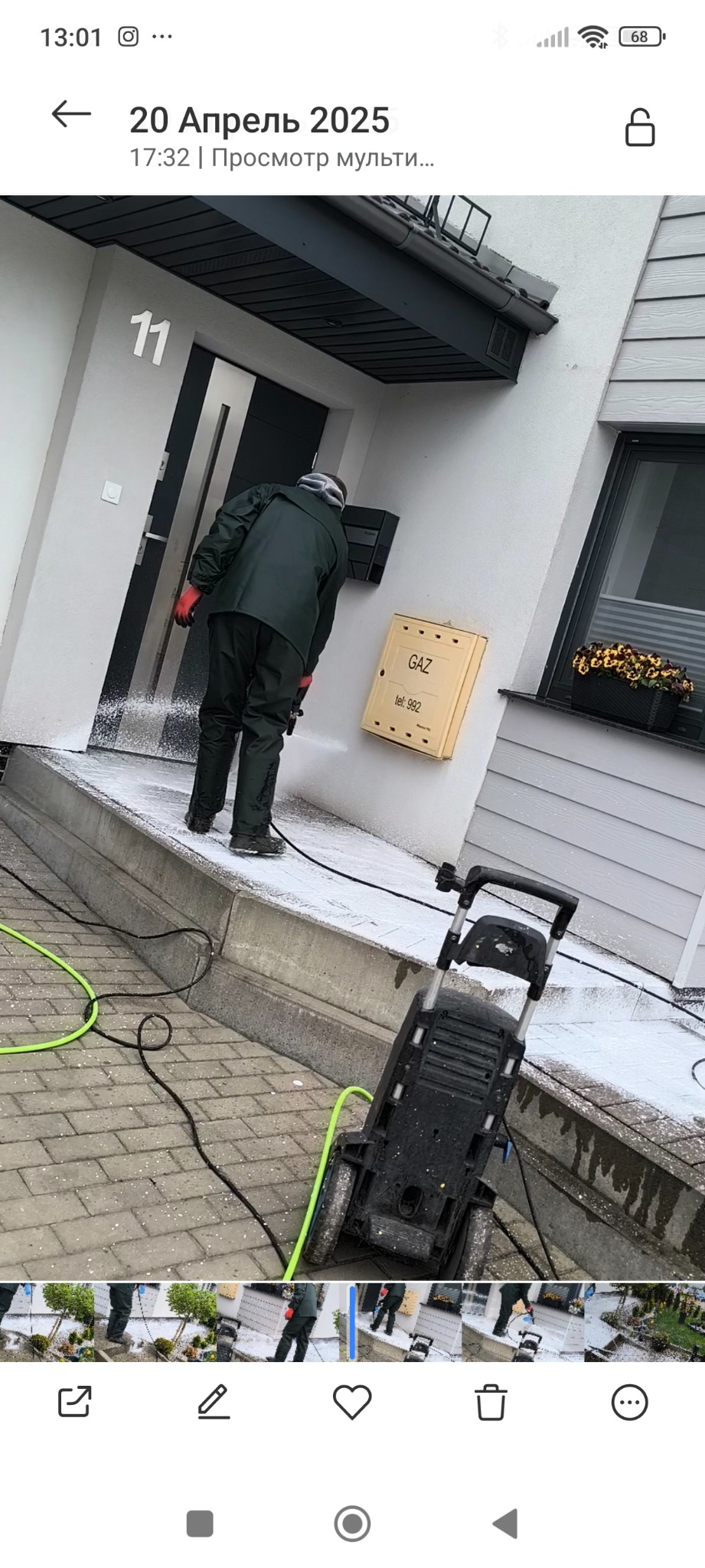 Czyszczenie elewacji domu myjką ciśnieniową. Widoczny pracownik w kombinezonie i urządzenie do mycia. Na ścianie skrzynka gazowa z numerem telefonu.