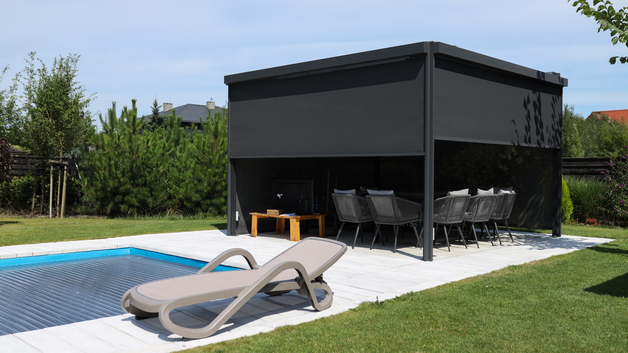 Nowoczesna altana z zasłoniętymi ścianami, obok basen z roletą, leżak i zadbany trawnik