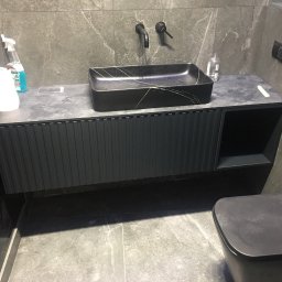 SoBo - Nowoczesna łazienka z czarną umywalką nablatową o marmurkowym wzorze, szafką pod umywalkę z ryflowanym frontem i szarą płytką imitującą kamień na ścianach i podłodze.