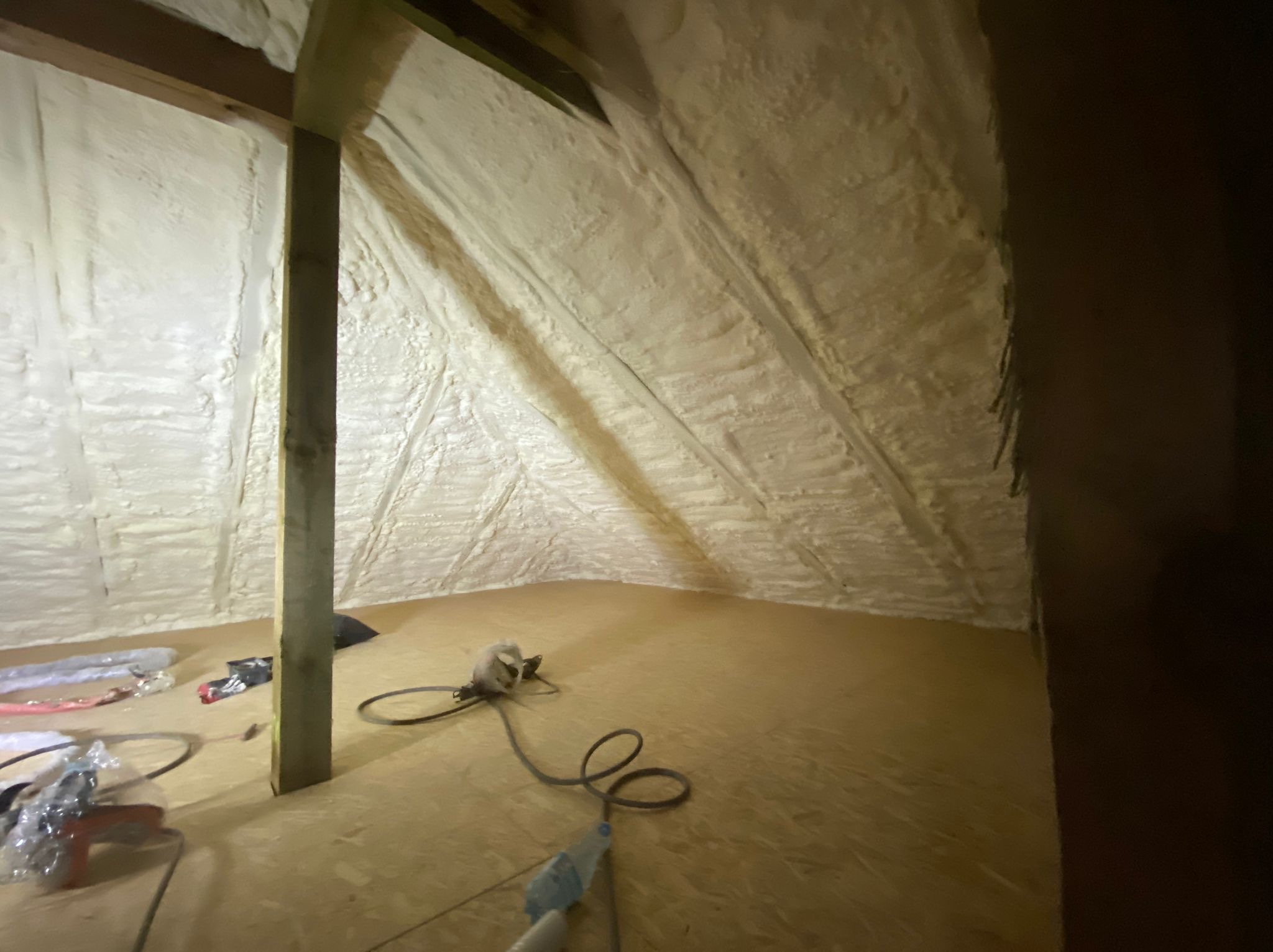 Poddasze po natrysku pianki izolacyjnej, widoczne narzędzia pracy i drewniana konstrukcja