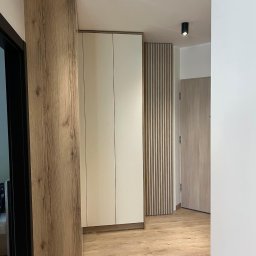 MG Meble na wymiar - Nowoczesna szafa w przedpokoju z drewnianymi akcentami i oświetleniem punktowym.