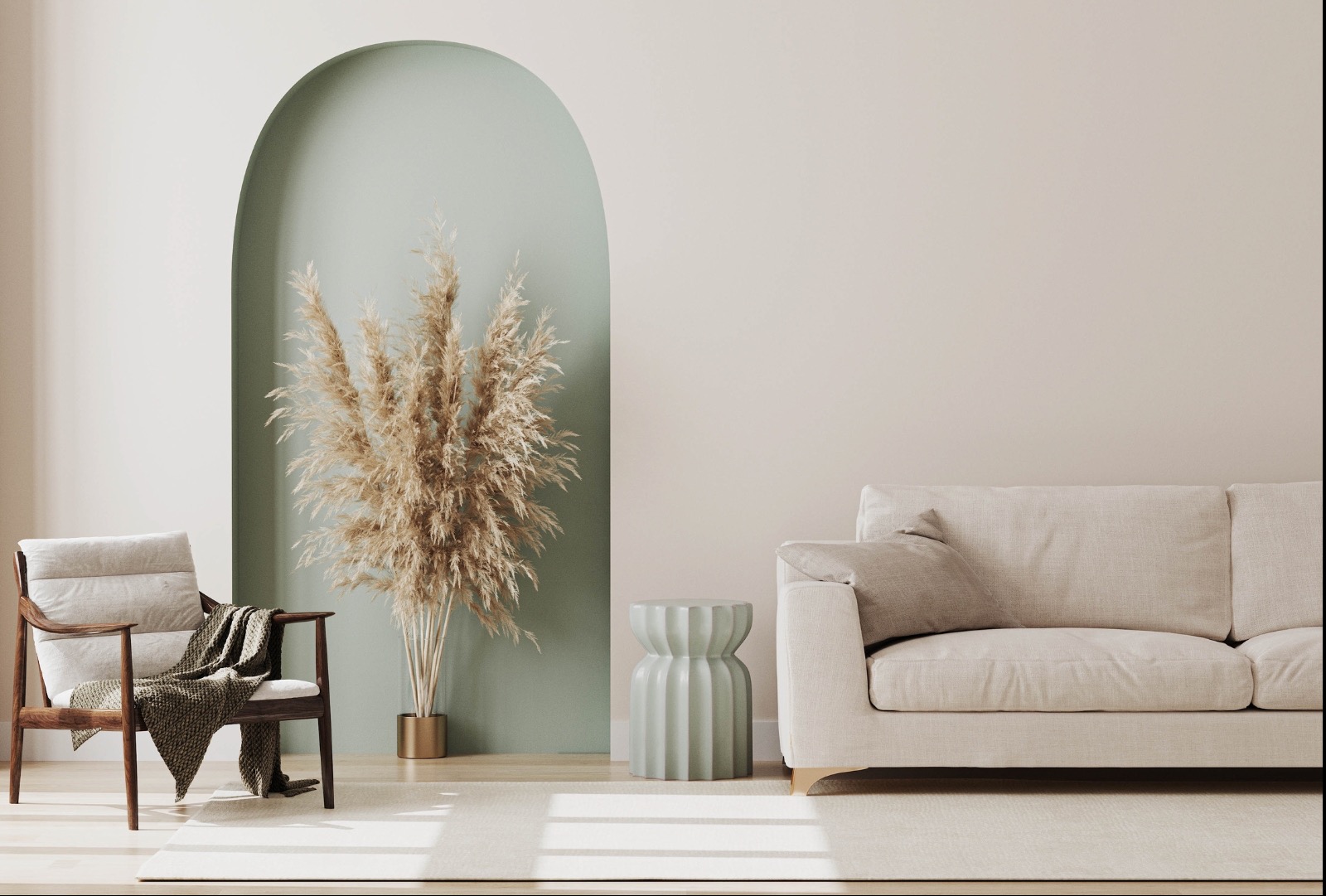 Jasne wnętrze z beżową sofą, drewnianym fotelem z pledem i dekoracyjną trawą pampasową w złotym wazonie, na tle zielonego łuku w ścianie.