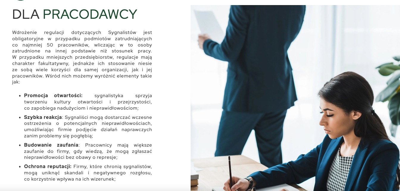 Kobieta w niebieskiej marynarce pisze w notatniku na biurku, obok stoi mężczyzna w garniturze, w tle widoczne materiały informacyjne dla pracodawców dotyczące sygnalistów.