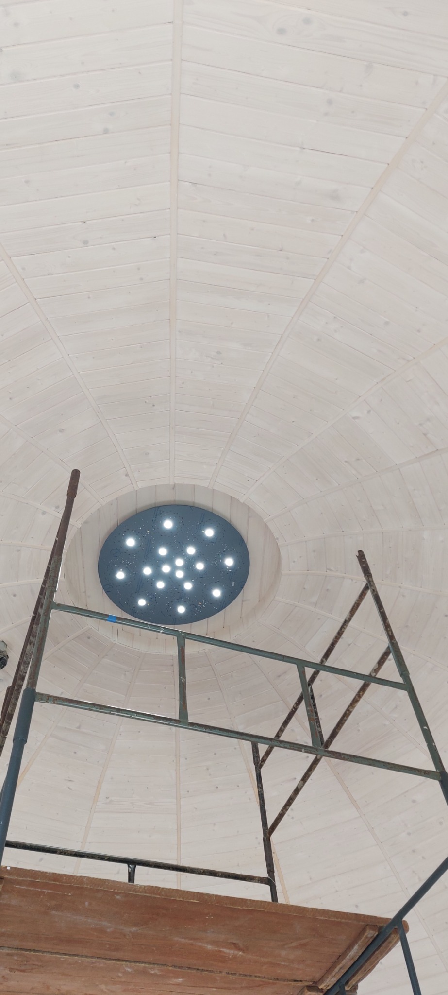 Drewniana kopuła sufitowa z zamontowanym okrągłym panelem oświetleniowym LED, widok z rusztowania.