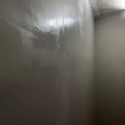 Ściana w rogu pomieszczenia po nałożeniu gładzi, widoczne ślady po szpachlowaniu na ścianie i suficie, przygotowanie do malowania.