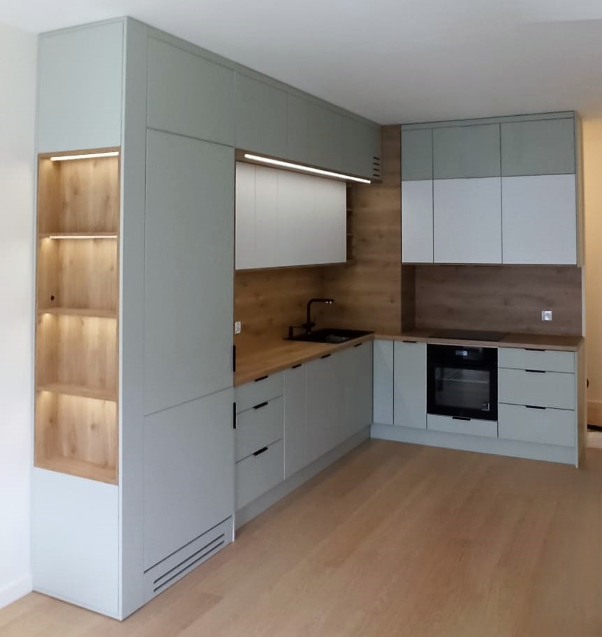 Nowoczesna zabudowa kuchenna w Gruszowie z szarymi frontami, drewnianym blatem i oświetleniem LED, z widoczną zabudowaną półką z podświetlanymi drewnianymi wnękami.