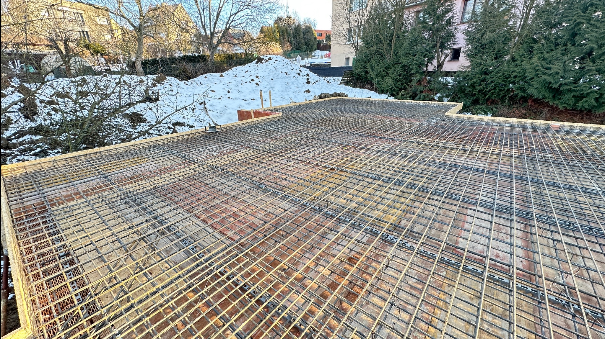 Zbrojenie stropu z siatki stalowej na podkładzie z cegły dziurawki, widok z góry w słoneczny dzień.