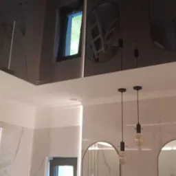 Nowoczesna łazienka z czarnym, lustrzanym sufitem podwieszanym, oświetleniem LED i dwoma wiszącymi lampami z żarówkami Edisona, odbicie okna w suficie.