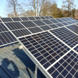 Visma-Tech - Panel słoneczny na dachu z widocznymi drzewami w tle, uchwycony pod kątem, z wyraźnie widoczną strukturą krzemową.