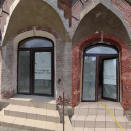 Porównanie stanu elewacji budynku przed i po renowacji, widoczne różnice w kolorze cegły i czystości fug, z otwartymi drzwiami wejściowymi z plakatem informującym o otwarciu salonu.