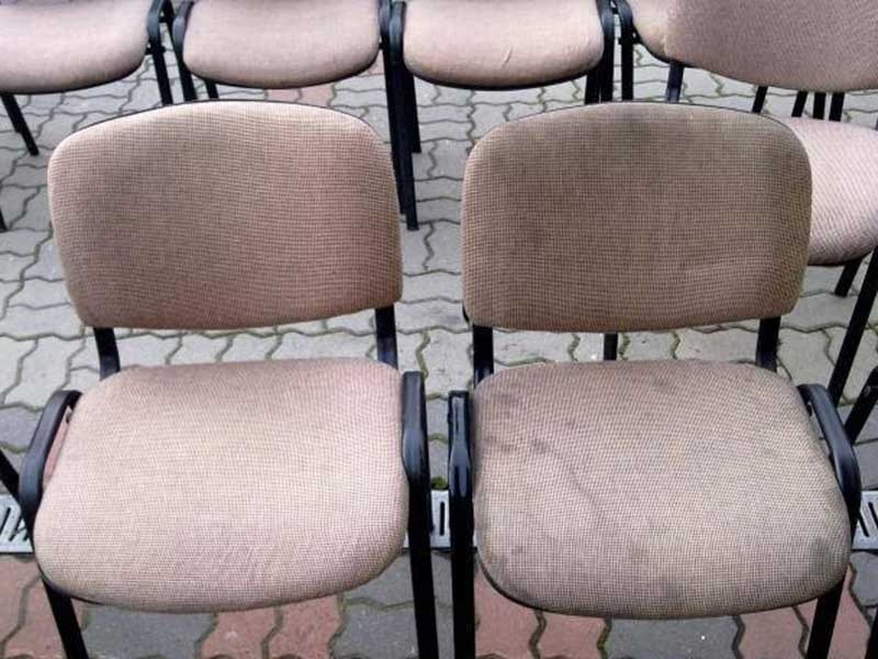Brudne, beżowe krzesła biurowe z tapicerowanymi siedziskami i oparciami, ustawione na kostce brukowej.