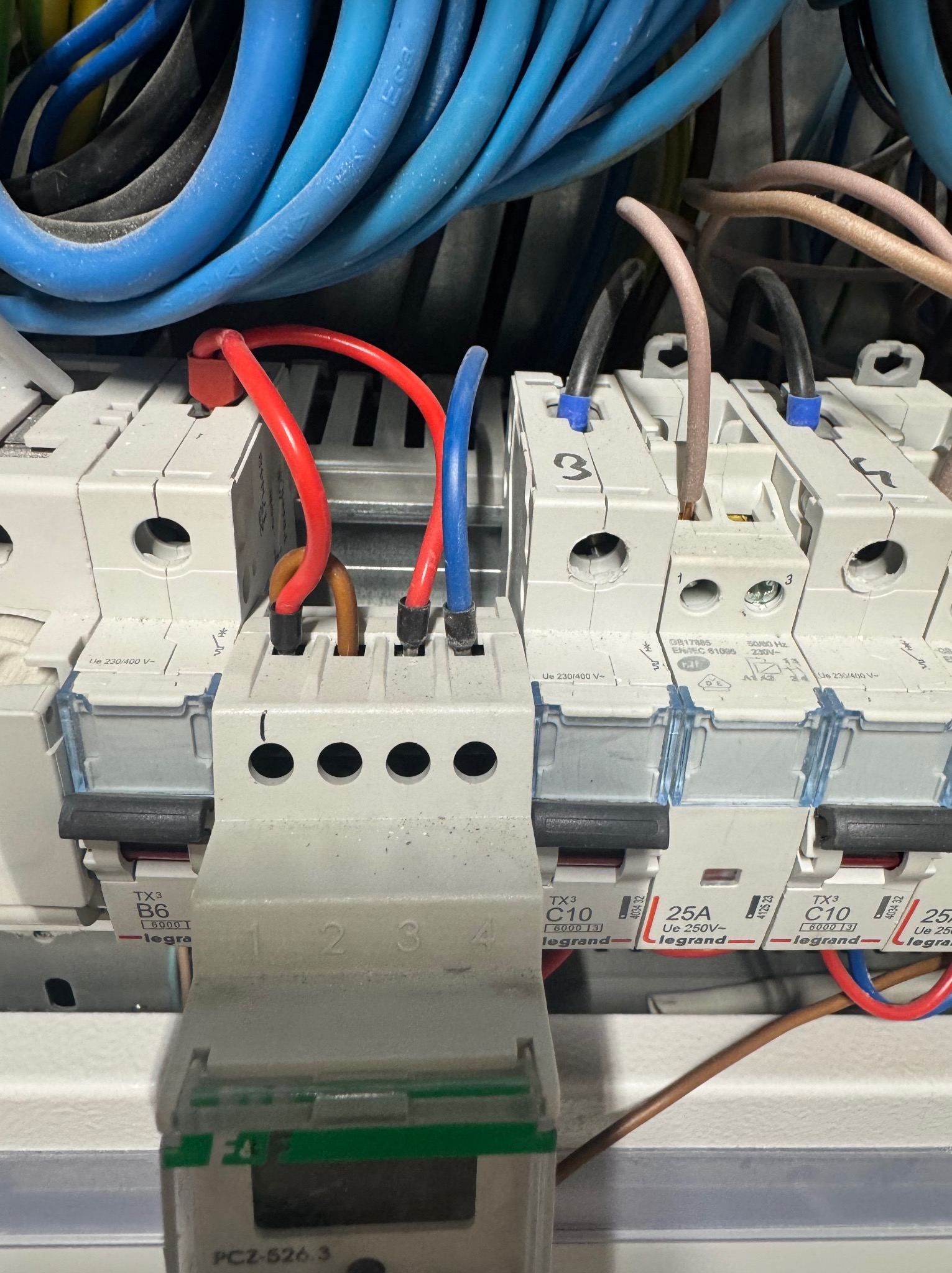 Szczegółowe ujęcie tablicy rozdzielczej z przewodami i bezpiecznikami Legrand, ukazujące podłączenia i oznaczenia. Element instalacji elektrycznej.