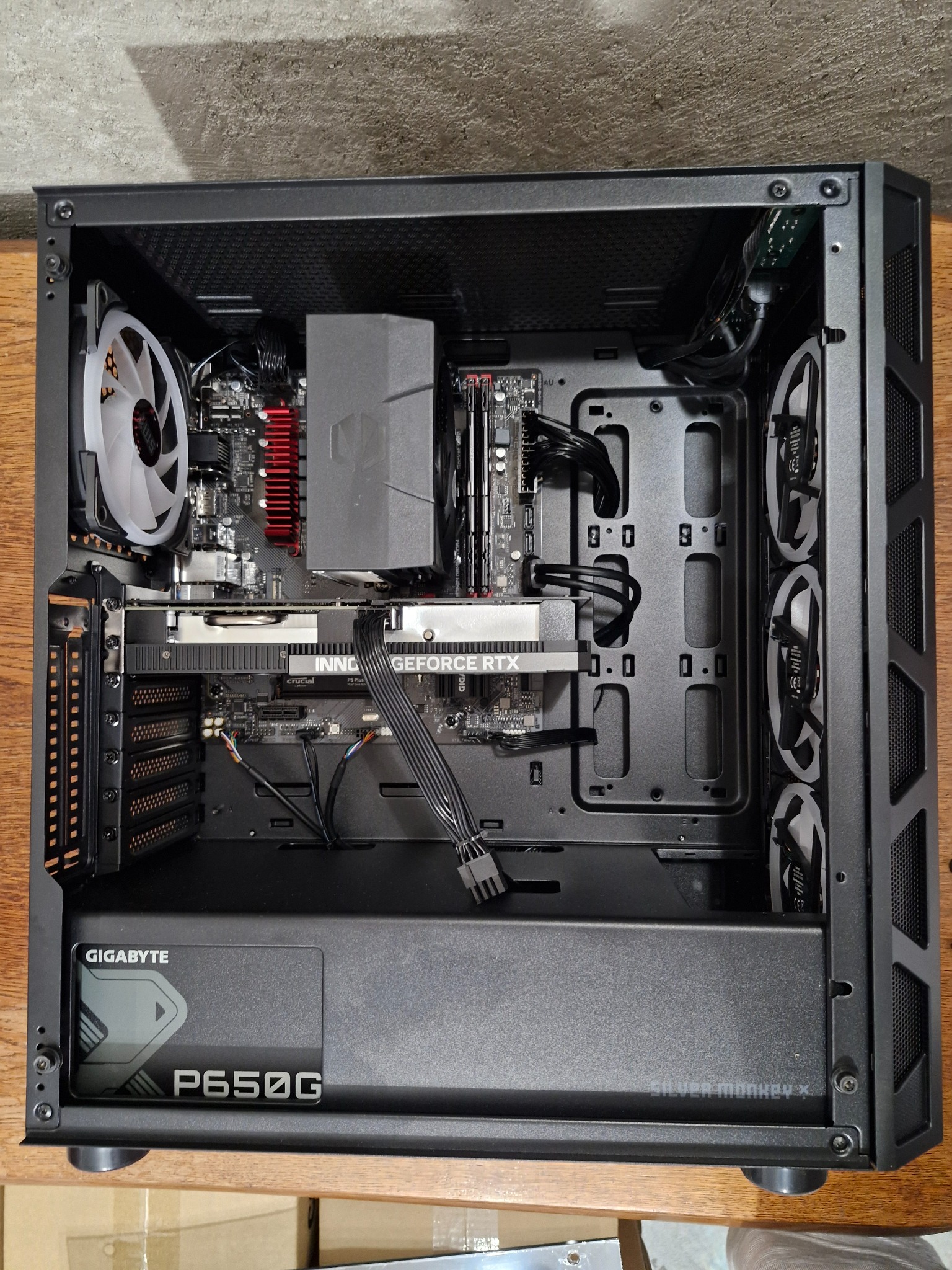 Wnętrze obudowy komputera stacjonarnego z zainstalowanymi komponentami: karta graficzna Inno3D GeForce RTX, płyta główna z czerwonym radiatorem, chłodzenie procesora, pamięć RAM, zasilacz Gigabyte...